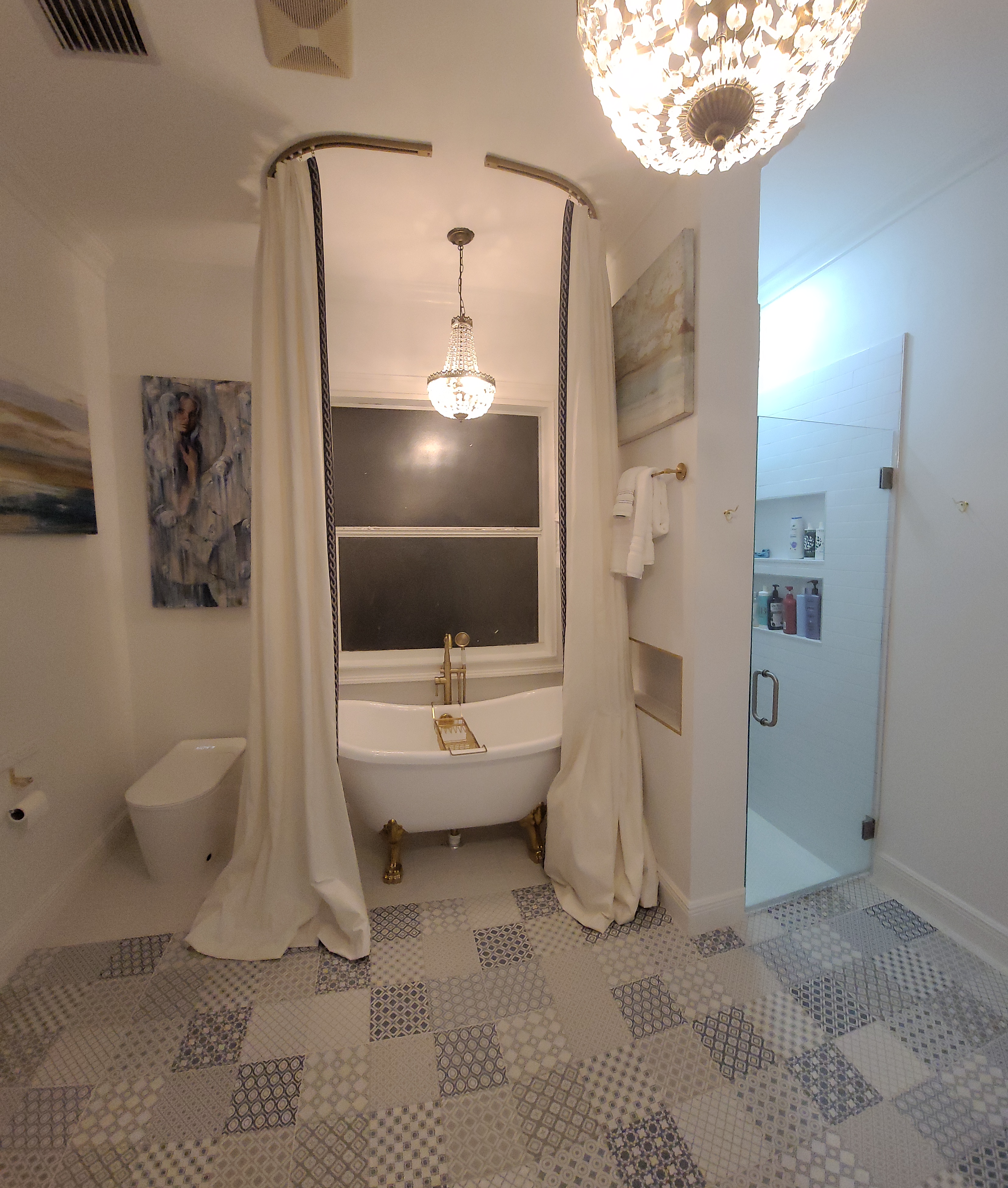 Clawfoot bathtub sanctuary at Maison Sarti with cream curtains and patterned tile